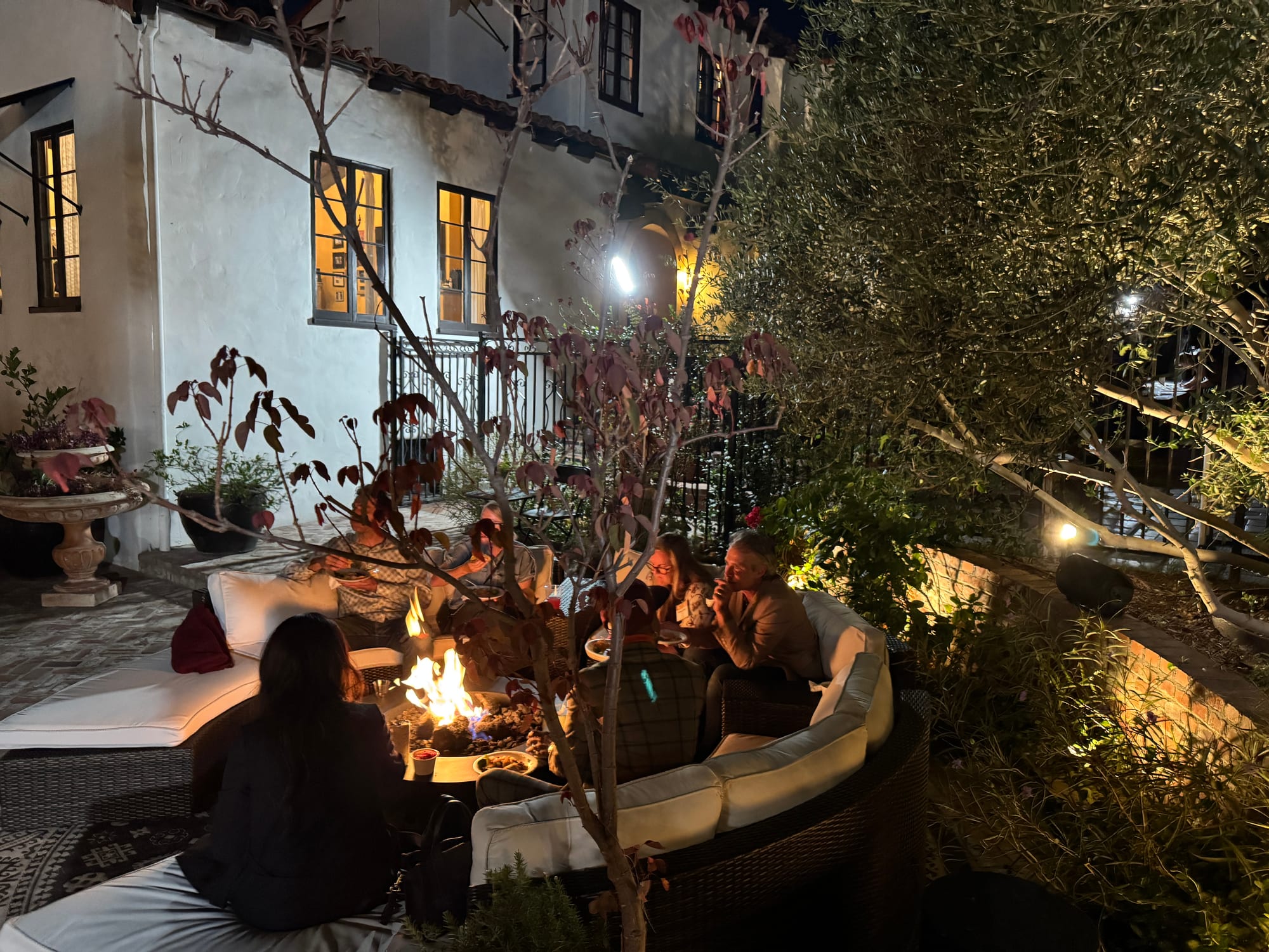 Guests gathered around a fire pit beside the house in the evening