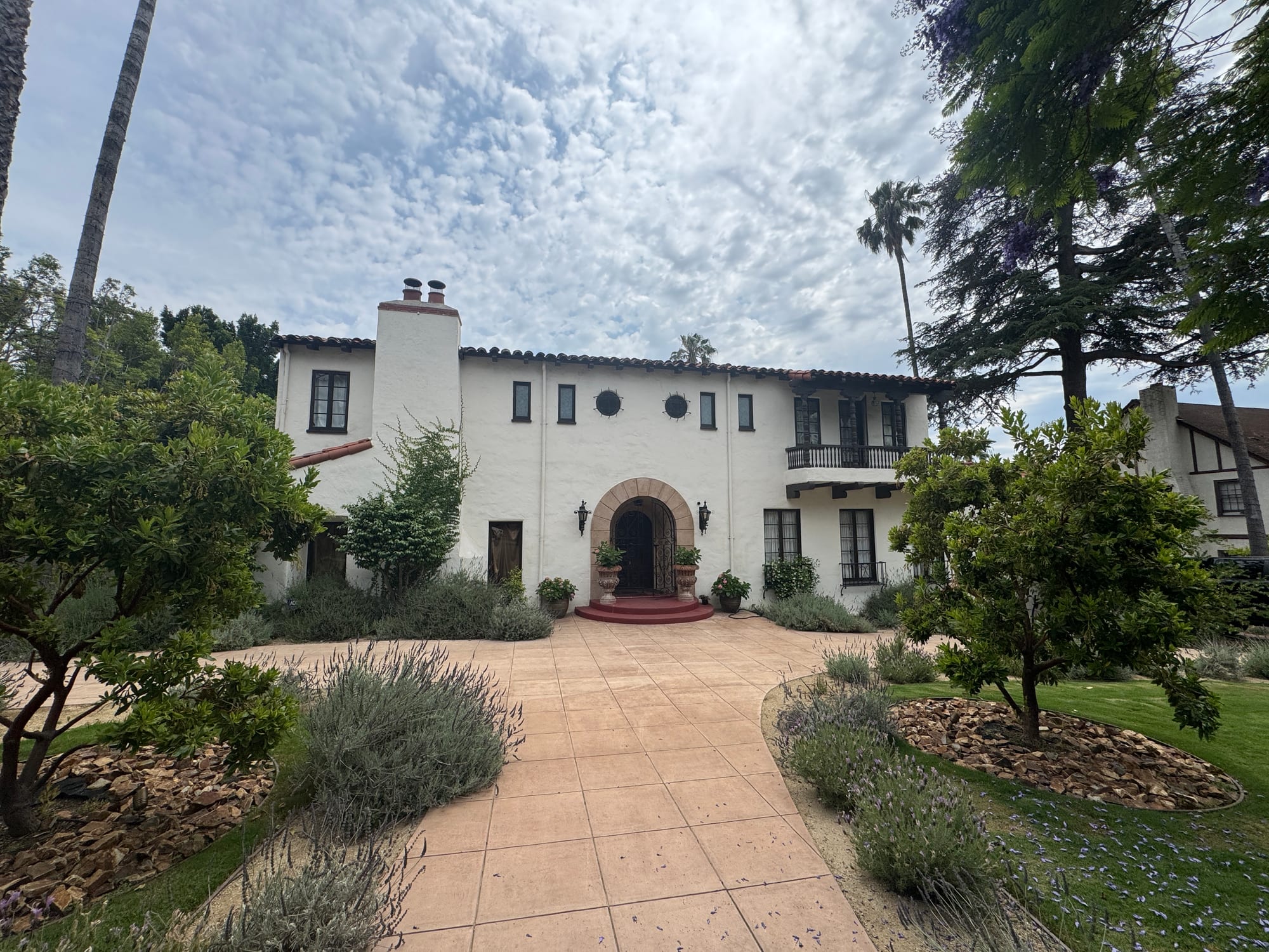 Full front facade and circular driveway framed by mature landscaping