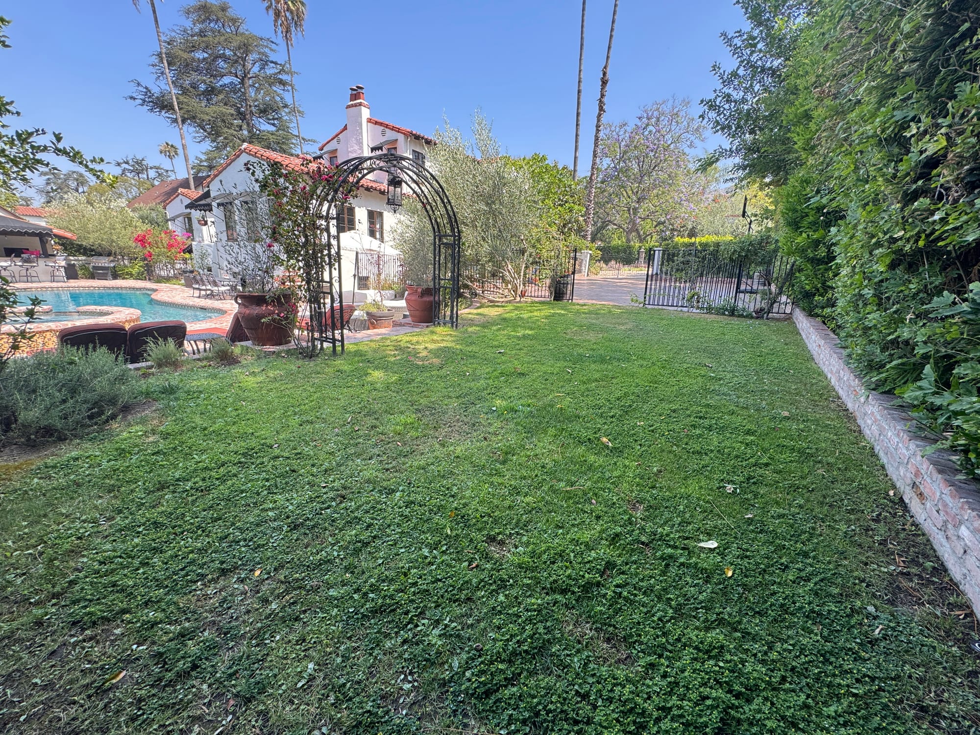 Rear lawn with a rose arbor and the pool beyond