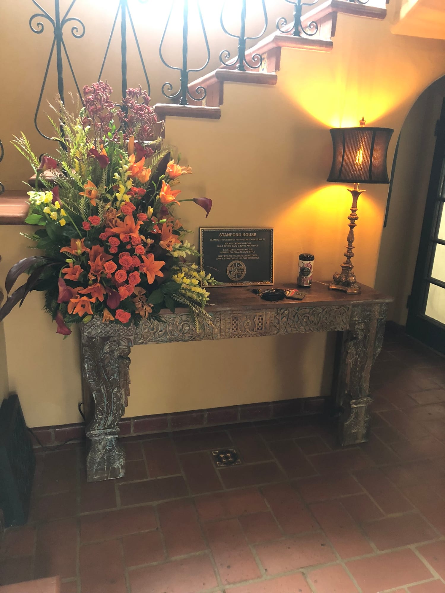 Floral arrangement beside the estate's historic plaque on a carved console