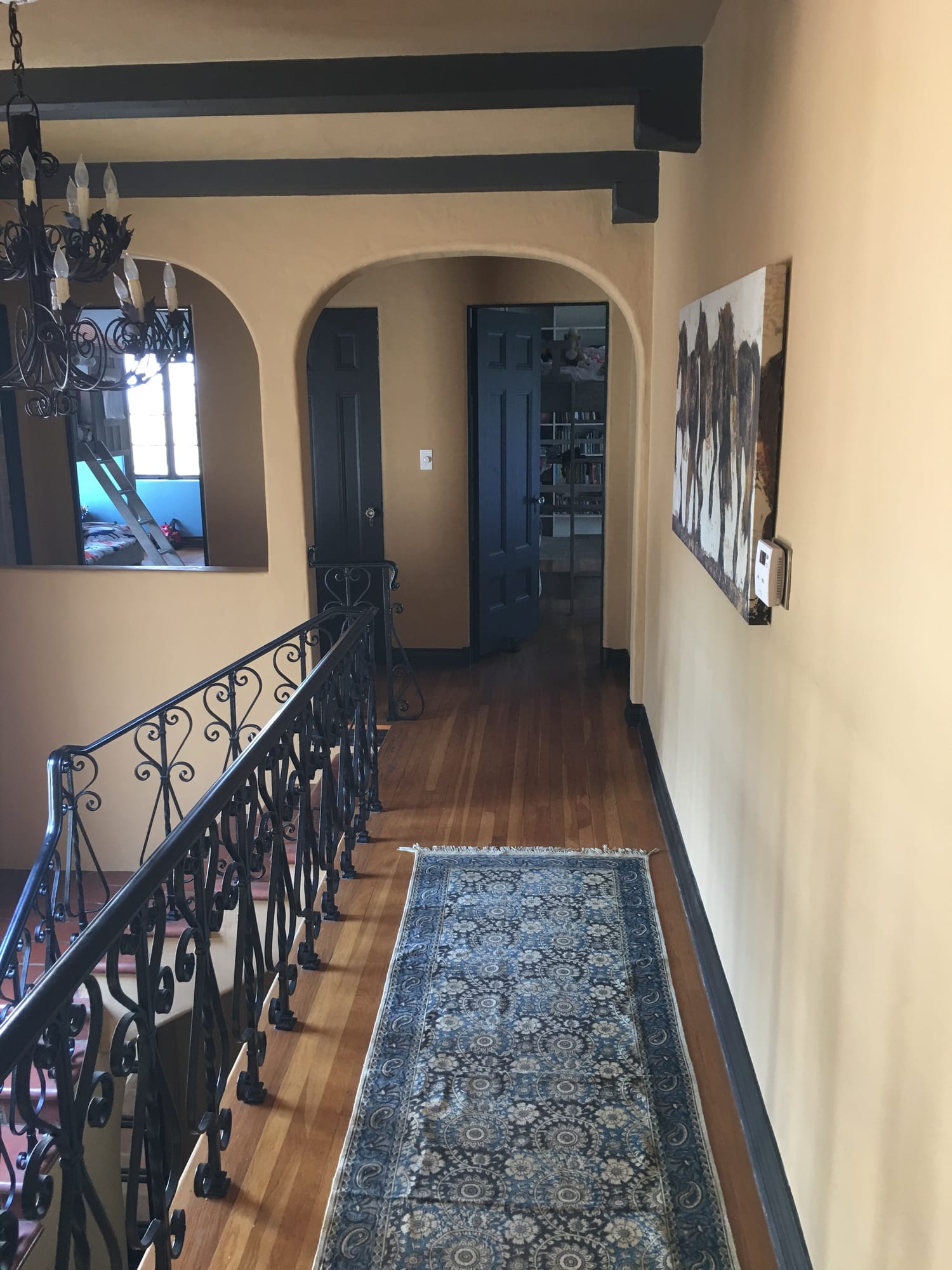 Upstairs landing with a wrought-iron railing and hardwood floors